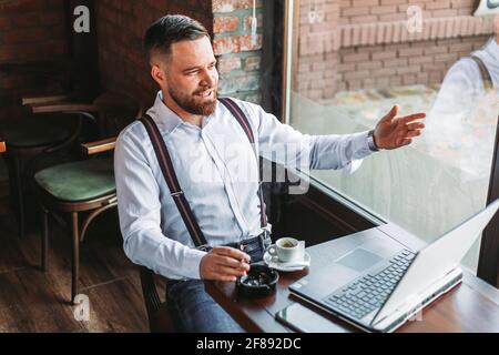 Junger Hipster Geschäftsmann mit einem Videoanruf in einem Café Stockfoto