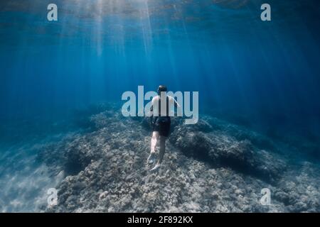 Männlicher Freitaucher gleitet ohne Flossen unter Wasser im blauen Meer Stockfoto