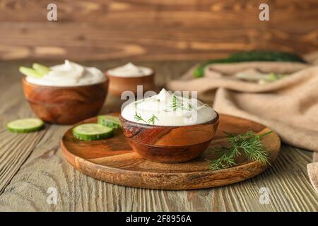 Schüsseln mit schmackhafter Sauerrahm auf Holzhintergrund Stockfoto