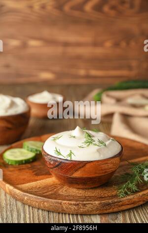 Schüsseln mit schmackhafter Sauerrahm auf Holzhintergrund Stockfoto