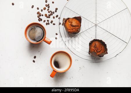 Tassen Kaffee mit Muffins auf hellem Hintergrund Stockfoto