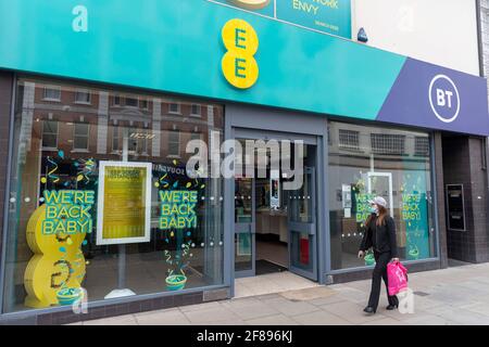 Eine Frau geht an einem EE-Laden in der Oxford Street vorbei, auf dem ein Schild mit der Aufschrift ‘We’re back Baby!’ steht Stockfoto