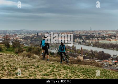 Zwei Radfahrer genießen Blick auf die Prager Skyline und Moldau, Tschechische Republik. Attraktive Landschaft mit tiefem Tal, Wanderwege, Prag Panorama Stockfoto