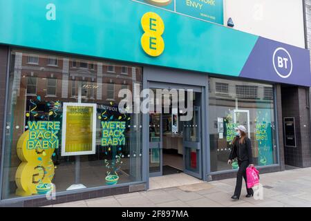 London, Großbritannien. April 2021. Eine Frau geht an einem EE-Laden in der Oxford Street vorbei, mit einem Schild auf dem Fenster, auf dem steht: ‘We're back Baby!' (Foto von Dave Rushen/SOPA Images/Sipa USA) Quelle: SIPA USA/Alamy Live News Stockfoto