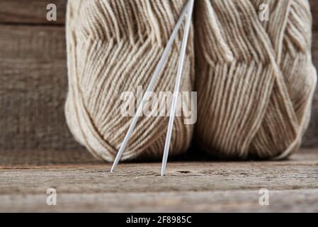Zwei Knäuel aus Wollgarn und Nadeln zum Stricken Holzhintergrund Stockfoto