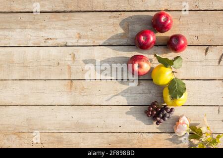 Rote Äpfel, reife Quitte und Trauben auf Holzhintergrund mit Kopierfläche Stockfoto