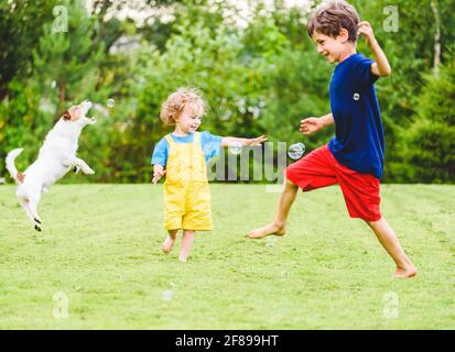 Kinder und Familie Haustier Hund spielen mit lustigen Seifenblasen An heißen sonnigen Sommertagen auf dem Hinterhof Rasen Stockfoto