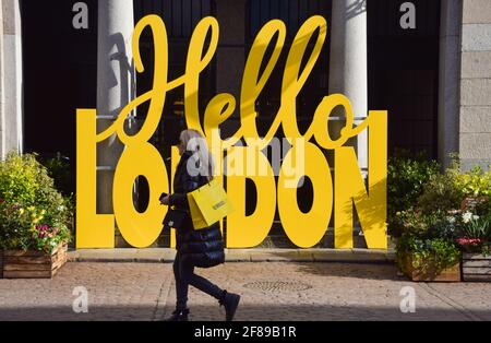 London, Großbritannien. April 2021. Eine Frau geht am Schild Hello London am Covent Garden Market vorbei. Geschäfte, Restaurants, Bars und andere Unternehmen haben heute nach fast vier Monaten wieder geöffnet, da sich die weiteren Sperrregeln in England lockern. Stockfoto