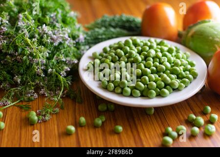 Gemüse auf dem Tisch enthält grüne Erbsen auf dem Teller mit Tomaten, bitterem Kürbis, Korianderpflanze und Brinjal. Selektiver Fokus verwendet. Stockfoto