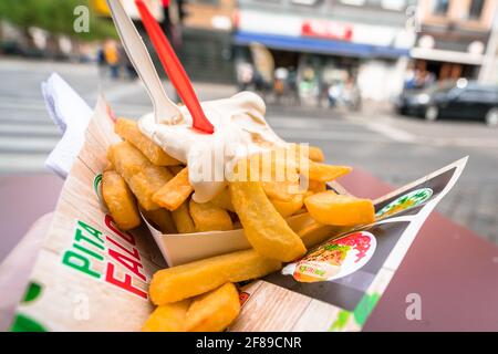 Antwerpen, Belgien - 04.29.2018: Traditionelle belgische Pommes auf Papier mit Sahnesauce und Kunststoffgabeln. Belgisches Street Food. Stockfoto