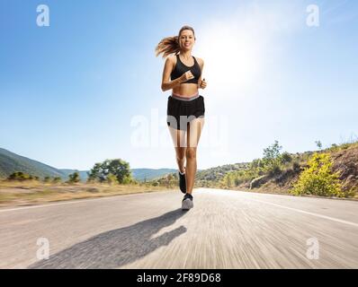 Porträt einer jungen Frau beim Joggen auf einem Straße in Richtung Kamera Stockfoto