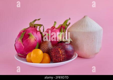 Mischen Sie exotische tropische Früchte auf dem Teller auf rosa Hintergrund. Gesunde Ernährung Konzept Stockfoto