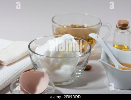 Inhaltsstoffe der Maske „Eierweiß“. Geschlagenes Eiweiß, Mandelöl, Honig, Kamillentee. Hausgemachte Kosmetik. Nahaufnahme. Stockfoto