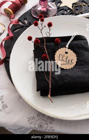 Gefaltete elegante schwarze Serviette auf einem Weihnachtsgericht mit dem Namen Chloe auf einem runden Anhänger. Stockfoto