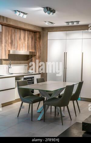 Interieur der trendigen weißen minimalistischen Küche mit klassischen Holzdetails, Luxus-Innenarchitektur. Moderne Pendelleuchten, minimalistisches Innendesign Stockfoto