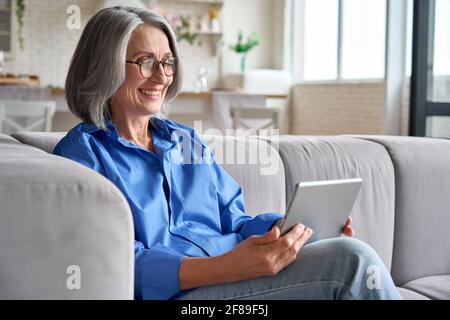 Ältere glückliche ältere Frau zu Hause bei einem Videogespräch mit dem Hausarzt. Stockfoto