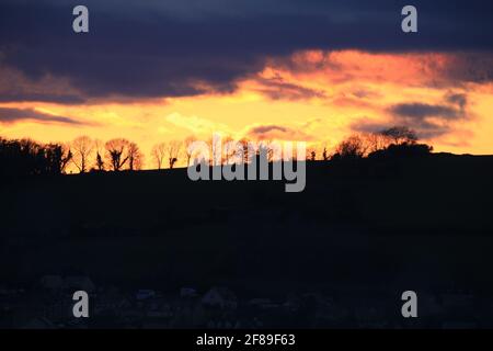 Stroud, Großbritannien, 12. April 2021. Wetter in Großbritannien. Sonnenuntergangsfarben über den Wäldern von Randwick in Stroud, Gloucestershire. Kredit: Gary Learmonth / Alamy Live Nachrichten Stockfoto