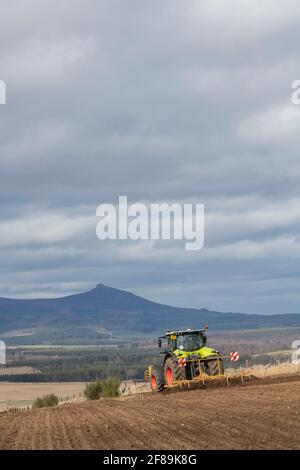 Ein Bauer bereitet mit einem Meißel ein Feld für die Kultivierung vor Pflügen in Aberdeenshire mit Blick auf Bennachie in der Entfernung Stockfoto