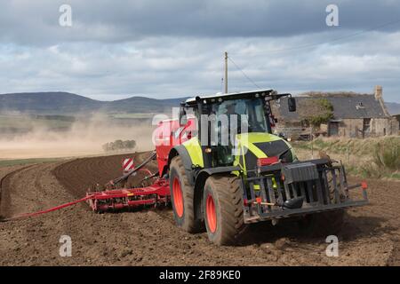 Vorderansicht eines Traktors, der einen Universal Seed zieht Bohren Sie in einem Feld im ländlichen Schottland Stockfoto