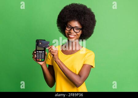 Foto von jungen fröhlich schönen afro Mädchen mit Kreditkarte Bargeldlose Zahlung am Terminal auf grünem Hintergrund isoliert Stockfoto