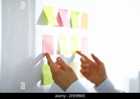 Nahaufnahme der Arbeiterhand mit bunten Papieren für Notizen mit Informationen Stockfoto