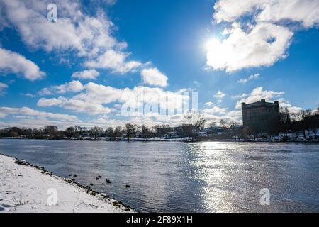 Schöne weser und verschneiten Deich mit Wasserturm in Der Hintergrund an einem warmen sonnigen Wintertag in bremen Stockfoto