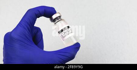Coronavirus-Impfung, Arzt Hand in blauen Handschuhen hält Impffläschchen, internationale Immunisierung Stockfoto
