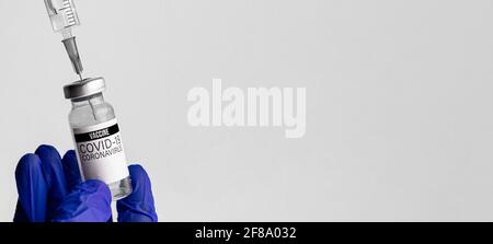 COVID-19 Impfstofffläschchen und Spritze in der Hand des Arztes, Healthcare Coronavirus Concept Banner mit Kopierraum Stockfoto
