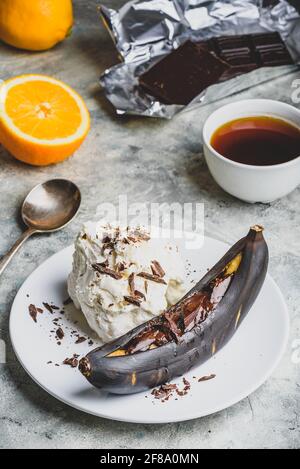 Süßes Dessert. Gegrillte Banane mit dunkler Schokolade, Zitronensaft und Vanilleeis. Stockfoto