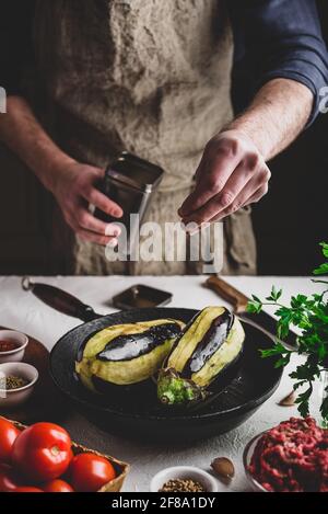 Auberginen zum Backen vorbereiten und mit Hackfleisch und Tomaten füllen. Salz bestreuen Stockfoto