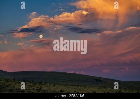 Vollmond in einem dramatischen Sonnenuntergang Himmel Stockfoto