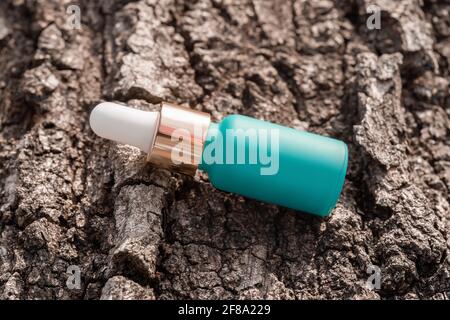 Kosmetisches Serum-Fläschchen-Mockup mit Pipette auf Baumrindenhintergrund Stockfoto