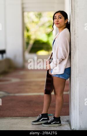 Zierlich asiatischer Teenager, der mit Ukulele steht Stockfoto