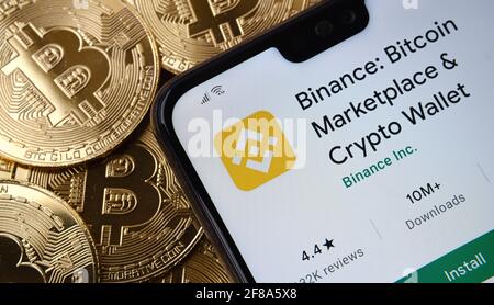 Binance-App auf dem Smartphone-Bildschirm auf dem oberen Bitcoin-Münzstapel platziert gesehen. Konzept. Stafford, Großbritannien, 12. April 2021. Stockfoto