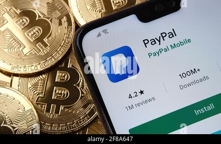 PayPal-App auf dem Smartphone-Bildschirm gesehen auf der Spitze Bitcoin Münzen Haufen platziert. Konzept. Stafford, Großbritannien, 12. April 2021. Stockfoto