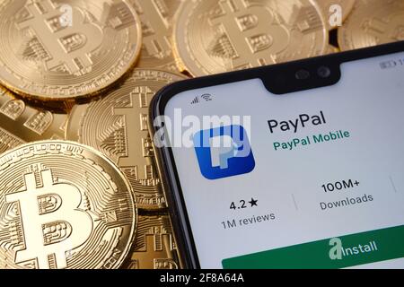 PayPal-App auf dem Smartphone-Bildschirm gesehen auf der Spitze Bitcoin Münzen Haufen platziert. Konzept. Stafford, Großbritannien, 12. April 2021. Stockfoto