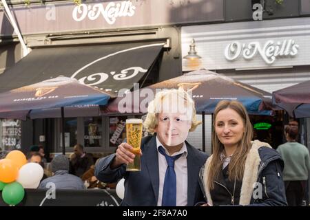 Die junge Frau posiert neben „Boris Johnson“ und hält ein Bier vor dem O'Neil Pub im Londoner West End, in der Nähe des Oxford Circus, Großbritannien Stockfoto