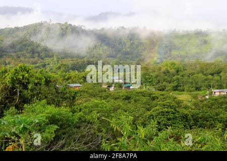 Leichter Regenbogen und Nebel über einem kleinen Dorf am Hang des Regenwaldes in Mindo, Ecuador Stockfoto