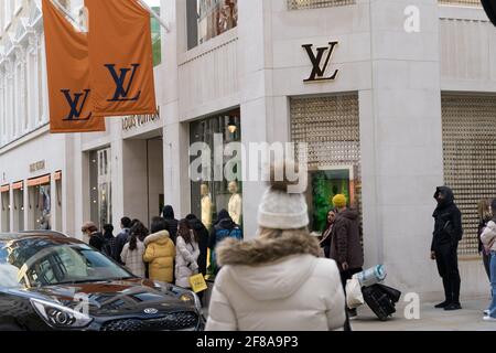 Vor dem Geschäft LV LOUIS VUITTON im Zentrum von London stehen die Käufer Schlange Stockfoto