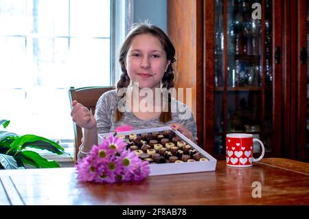 Lächelnd vor dem Teenager mit einer Schachtel Pralinen und Blumen Stockfoto