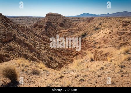 Blick über stark erodierte Canyons in der Wüste von New Mexico, entfernter Bergrücken, horizontaler Aspekt Stockfoto