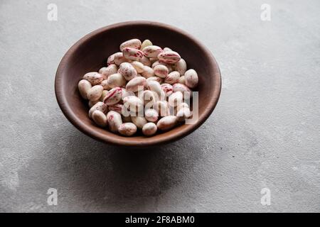 Geschälte Cranberry Borlotti Bohnen in Holzschale auf grauem Hintergrund Stockfoto