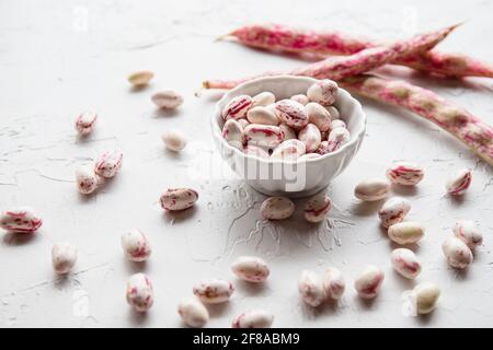 Geschälte Cranberry Borlotti Bohnen in White Bowl mit losen Bohnen Auf weißem Hintergrund Stockfoto