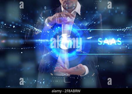 Business, Technologie, Internet und Netzwerkkonzept. Junger Geschäftsmann arbeitet auf einem virtuellen Bildschirm der Zukunft und sieht die Inschrift: SAAS Stockfoto