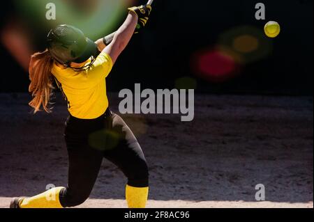 Eine weibliche Baseballspielerin schwingt für die Zäune Stockfoto