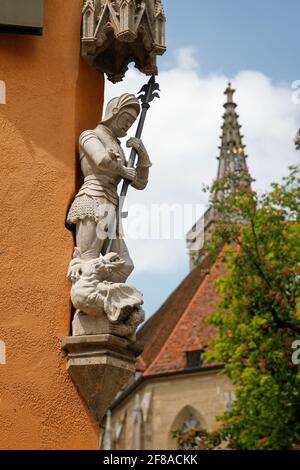 Geschnitzte Statue des Ritters mit Drache auf Gebäude mit Kirchturm Im Hintergrund bei Rothenburg ob der Tauber mit Blue Sky Stockfoto