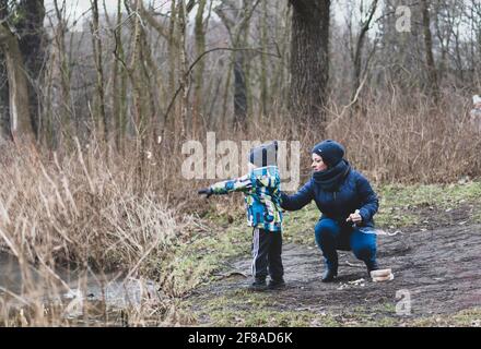 POZNAN, POLEN - 18. Feb 2018: Unbekannte Frauen und Jungen werfen an einem kalten Wintertag im Debinski-Wald Brotstücke ins Wasser Stockfoto