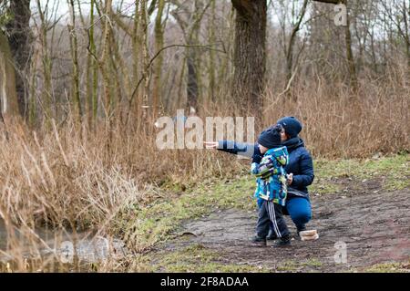 POZNAN, POLEN - 18. Feb 2018: Nicht identifizierte Frauen und Jungen werfen an einem kalten Wintertag Brot in einen Teich im Debinski-Wald Stockfoto