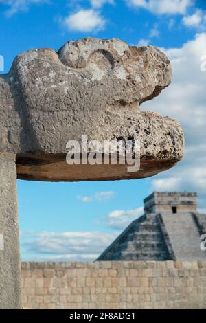 Geschnitzte Steinschlange mit Pyramide im Hintergrund vor blauem Himmel in Chichen Itza, Mexiko Stockfoto