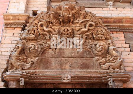 Aufwändig geschnitzter Holzrahmen über der Tür mit Gottheiten und Kreaturen in Bhaktapur, Nepal Stockfoto